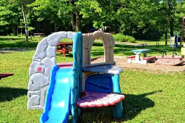 Parc de jeux extérieur avec toboggan et balançoires.