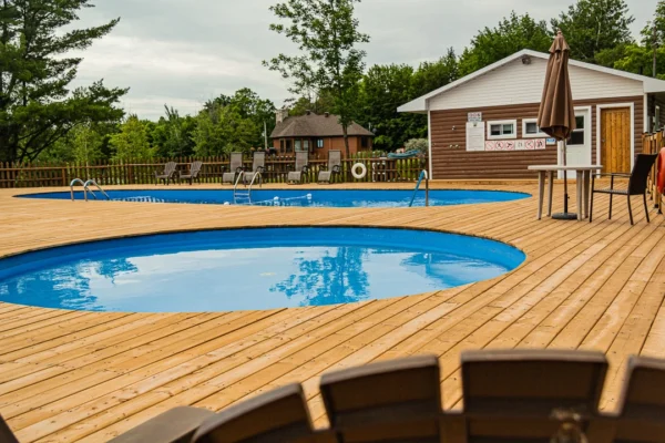 Piscine extérieure avec terrasse en bois et chaises longues.