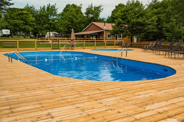 Piscine creusée entourée de terrasse en bois.