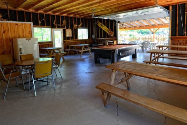 Intérieur rustique avec billard et tables en bois.