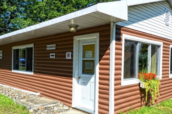 Petite buanderie extérieure entourée d'arbres verts.
