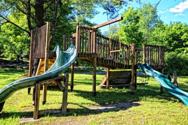 Aire de jeux en bois avec toboggans et balançoire.