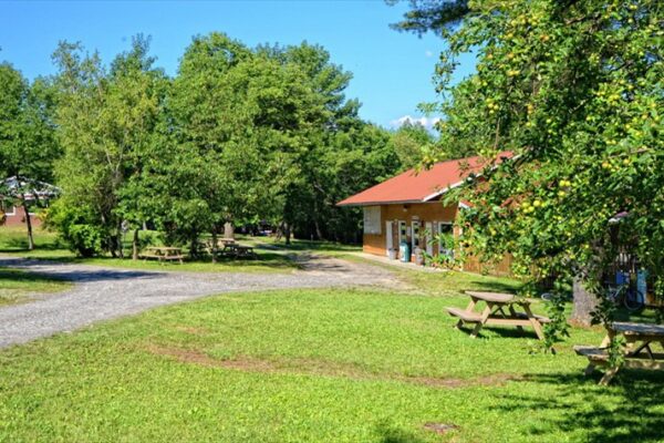 Parc verdoyant avec tables de pique-nique et bâtiments.
