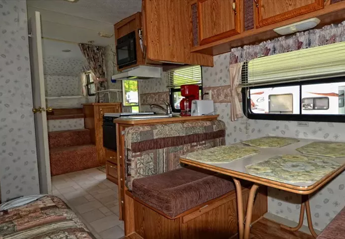 Intérieur d'une caravane avec kitchenette et table.